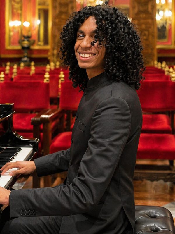 Músico con traje negro elegante tocando piano en un salón de celebración